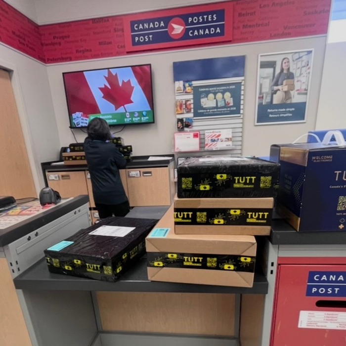 TUTT™ product boxes ready for shipping at a Canada Post office, showcasing trusted Canadian electronics delivery.