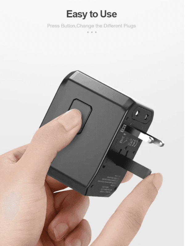 Hand holding a black universal travel adapter with sliding plug, easy to use, TUTT