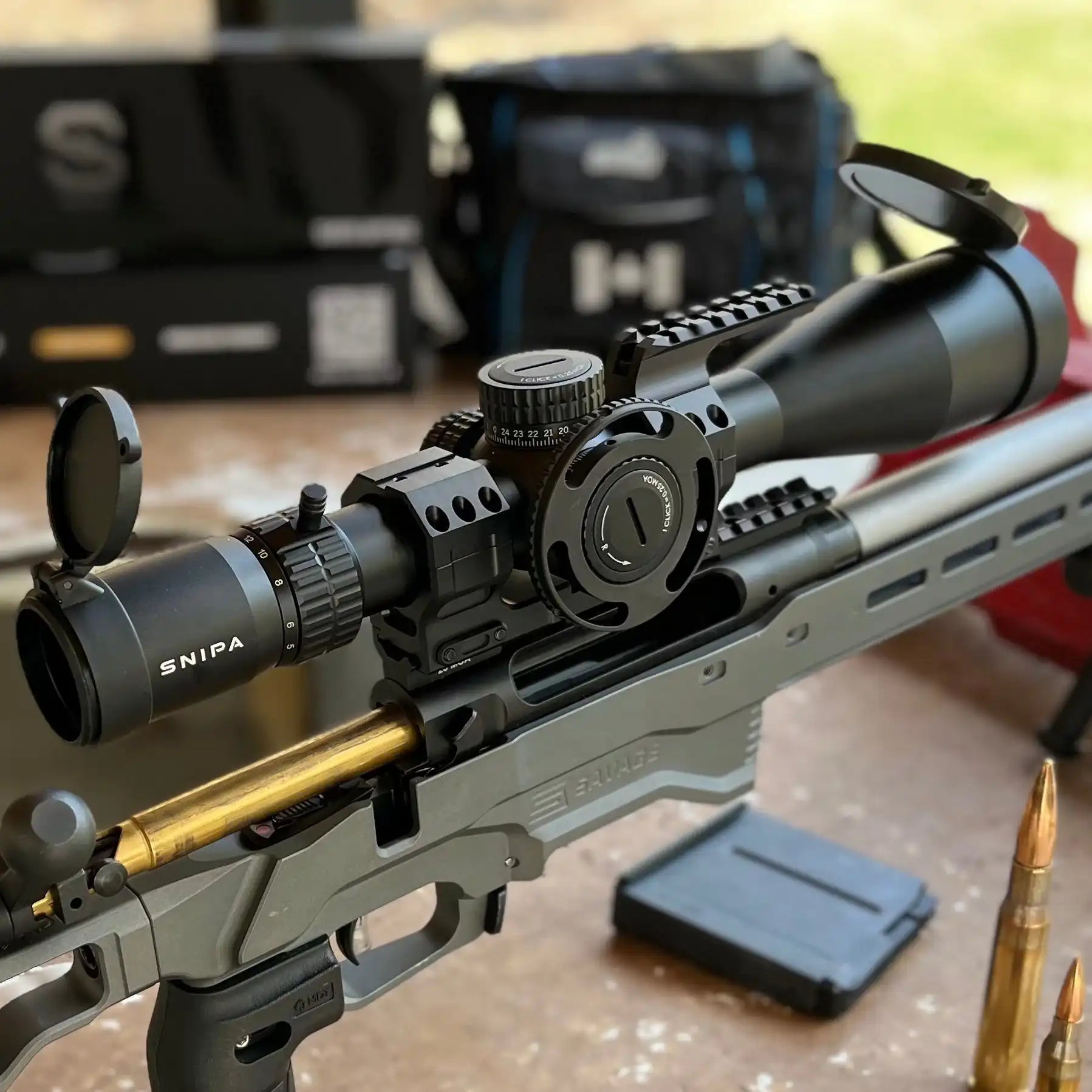 SNIPA Rockies X 5-25x56 FFP rifle scope with illuminated reticle and tactical mount on a Savage rifle, close-up on outdoor table. TUTT