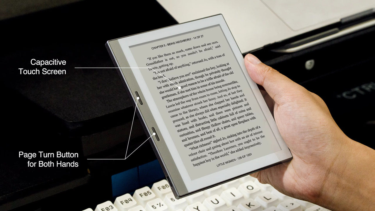 Hand holding e-reader with capacitive touch screen and page turn buttons beside keyboard background TUTT