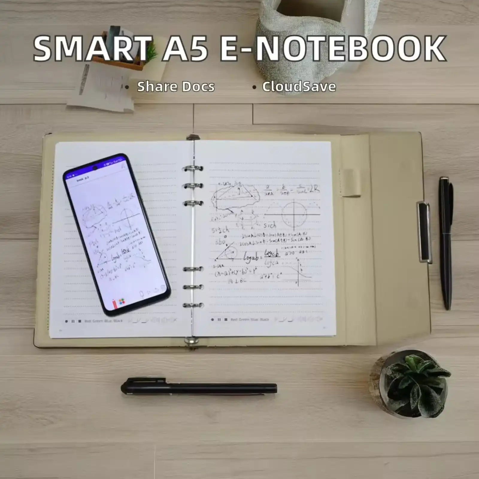 Open smart A5 e-notebook displaying handwritten math notes with a smartphone scanning the page, pens, and small plants on wooden desk TUTT