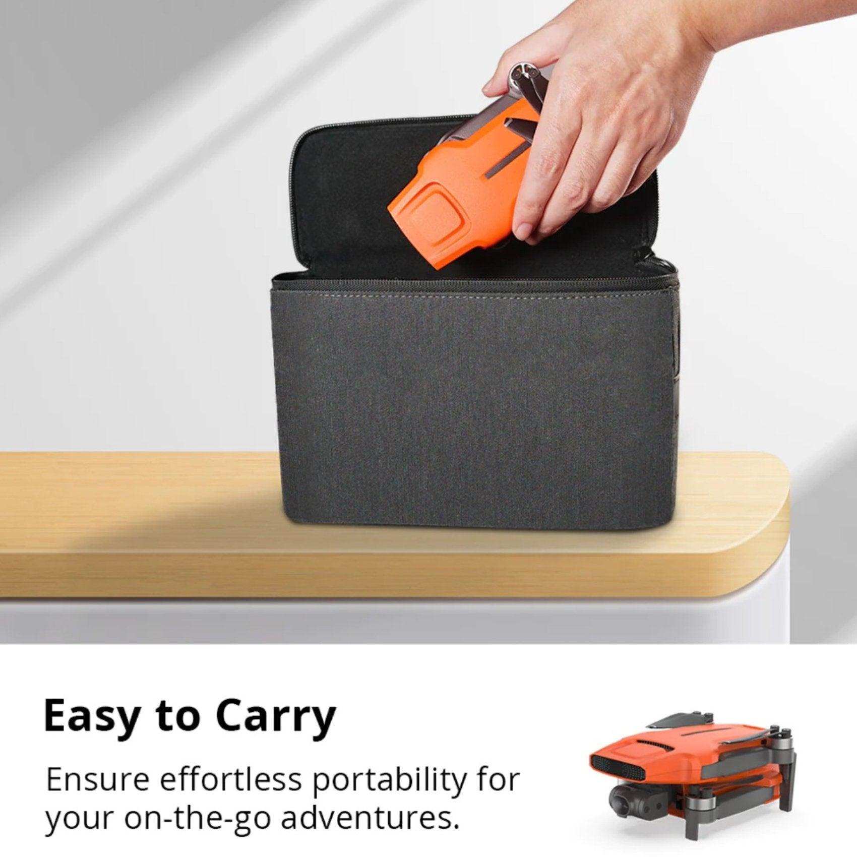 Hand placing orange FIMI X8 Mini V2 4K drone into black carrying case on table, ultra-lightweight. TUTT