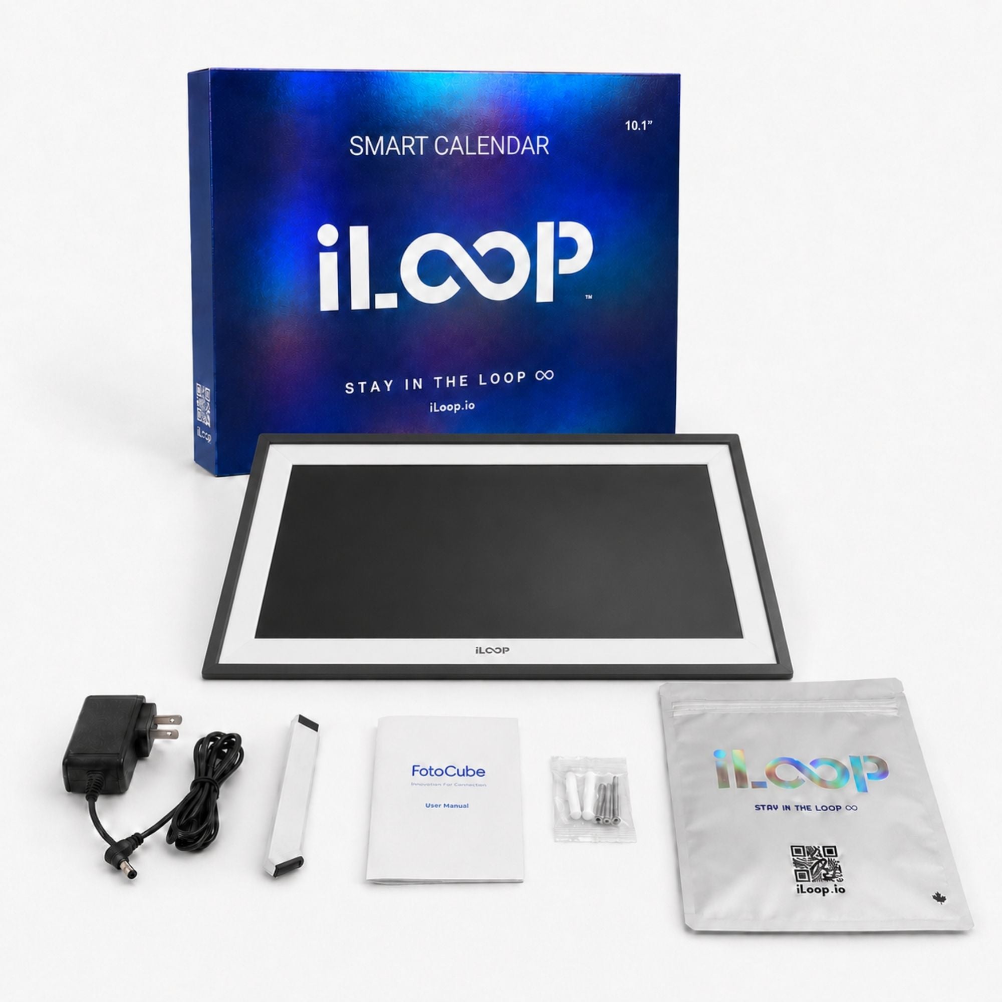 iLoop smart calendar display with its blue retail box, shown with accessories including a power adapter, cable, remote, instruction booklet, and a photo cube on a white background.
