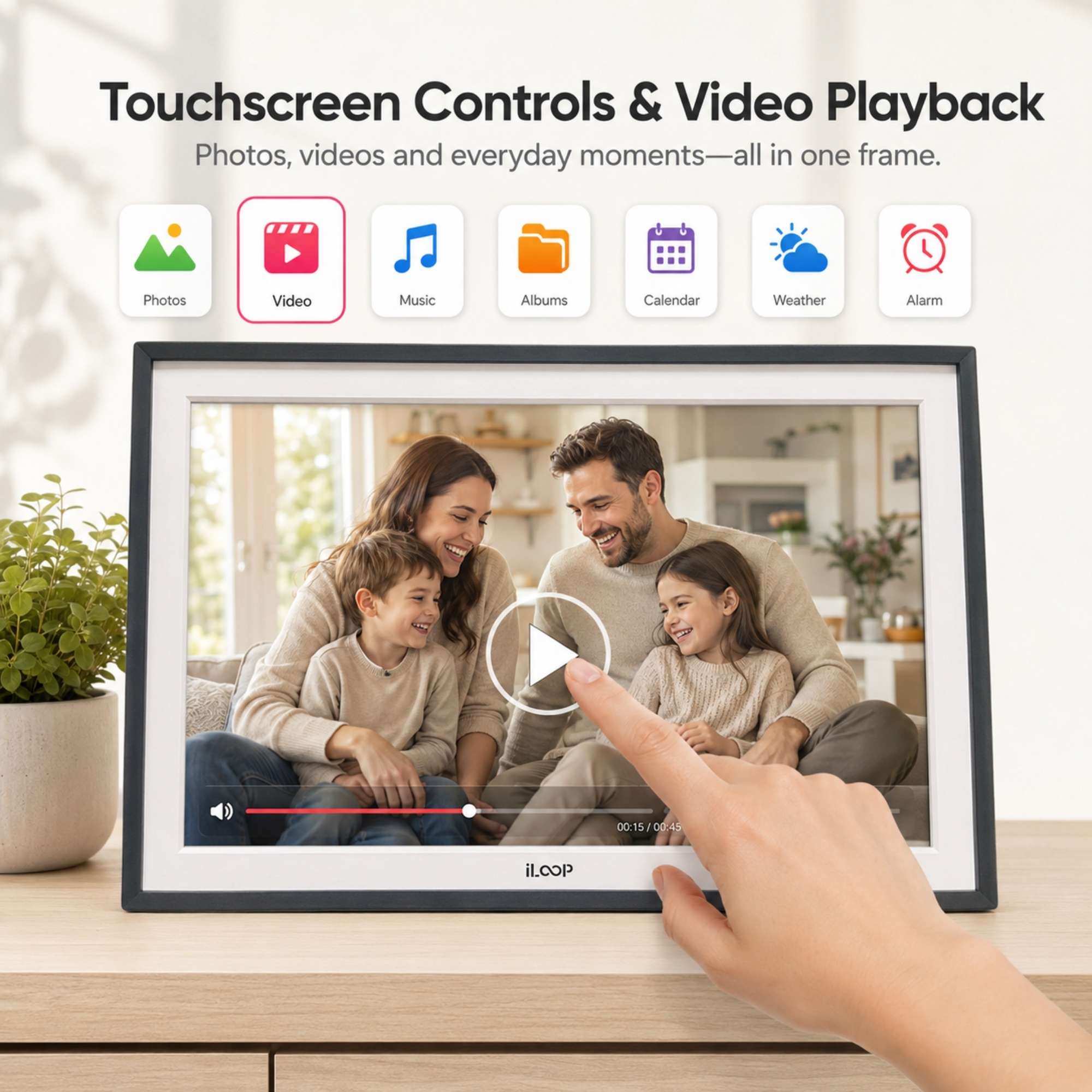 A digital photo frame with a black bezel and screen, shown on a tabletop with a hand touching the screen to demonstrate touchscreen controls and video playback. The image includes feature icons for photos, video, music, albums, calendar, weather, and alarm, and the brand name ILOOP at the bottom of the frame.