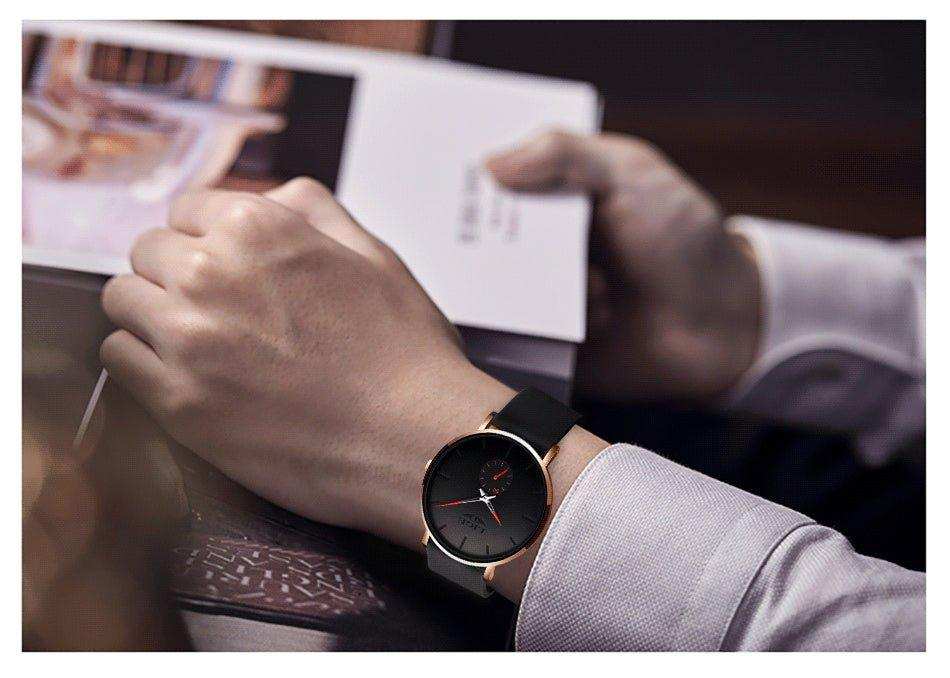 Man wearing a LIGE classic quartz watch with black strap and round black face, reading a book TUTT