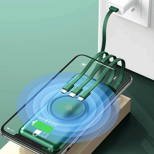 Green 30000mAh wireless portable charger power bank with built-in cables charging a phone, LED display visible, fast charging, on green surface. TUTT