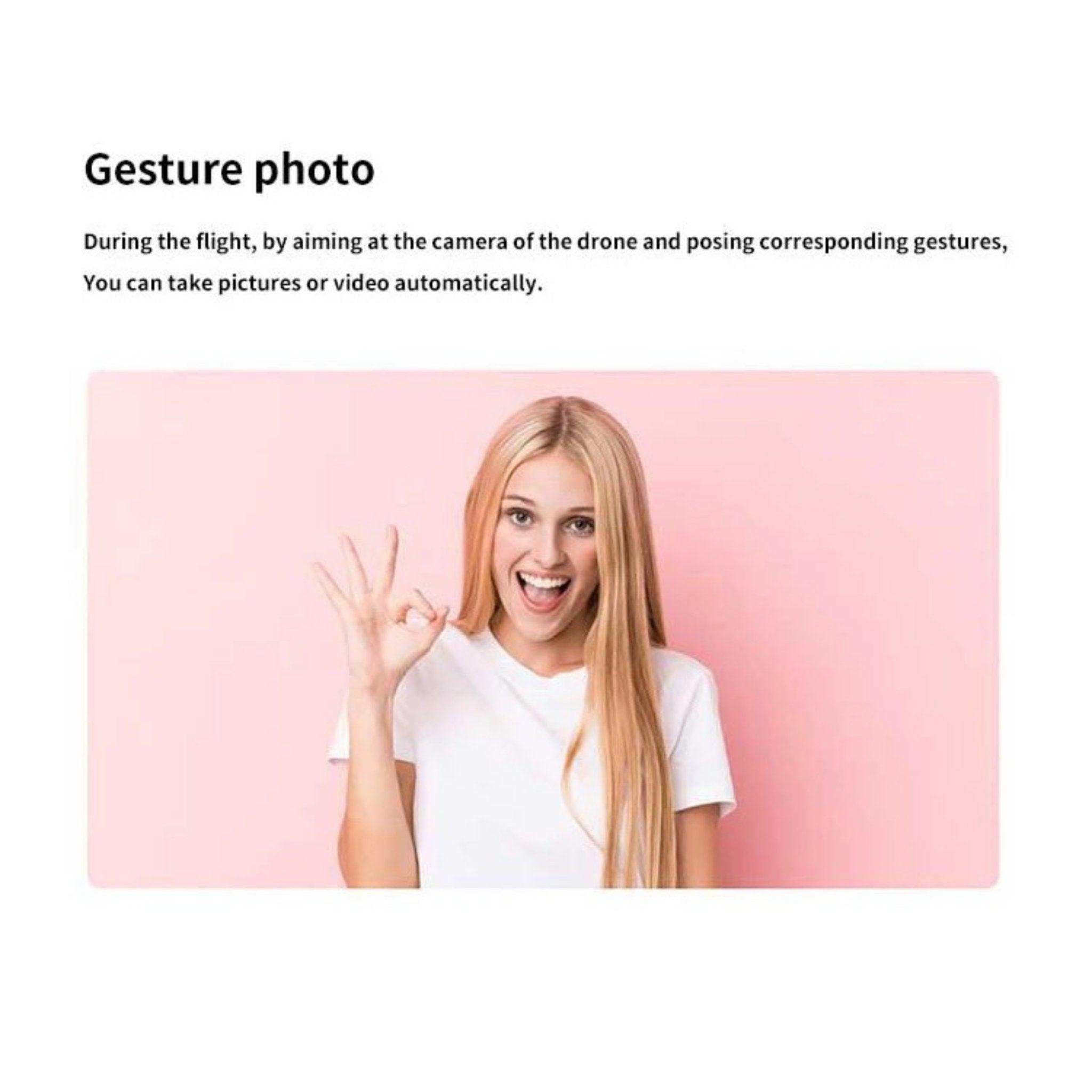 Blonde woman in white shirt makes OK gesture for drone gesture photo feature on pink background, TUTT