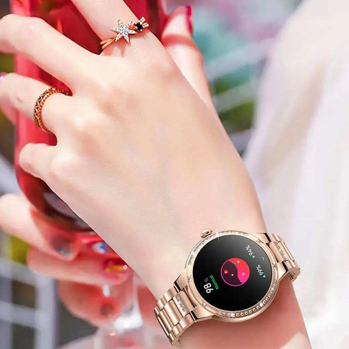 Rose gold ladies AMOLED smart watch with health tracking on wrist, holding red glass, TUTT