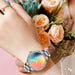 Elegant ladies' silver AMOLED screen smartwatch on wrist, holding peach roses bouquet, TUTT