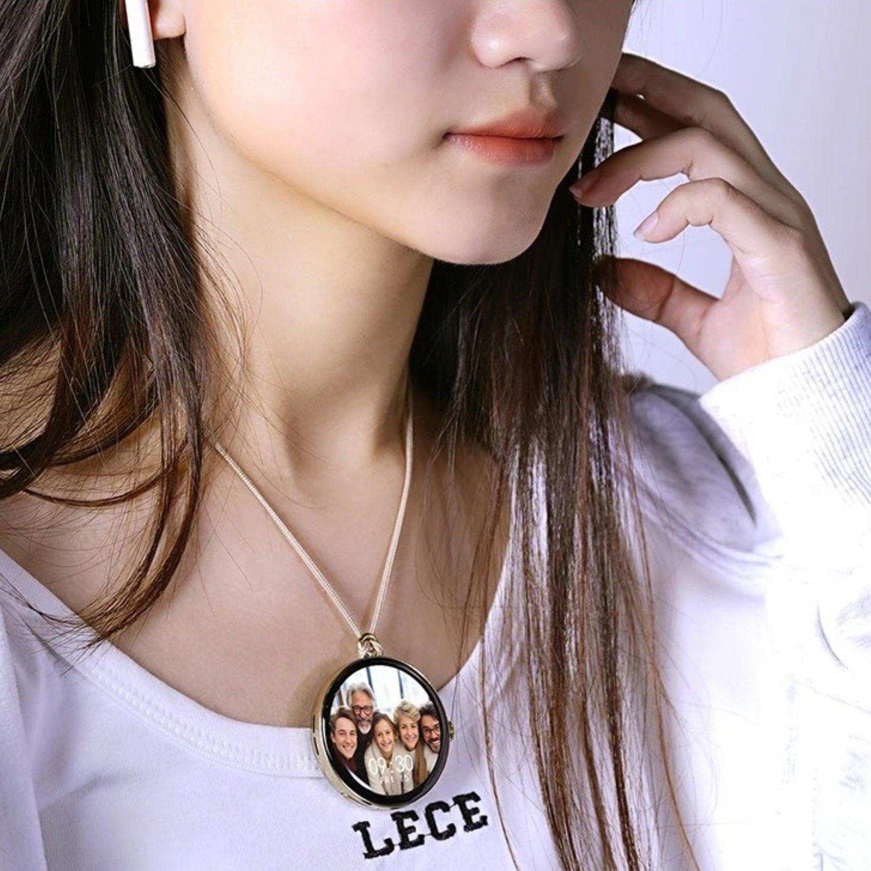 Woman wearing a round digital locket necklace displaying a group photo and time on screen TUTT