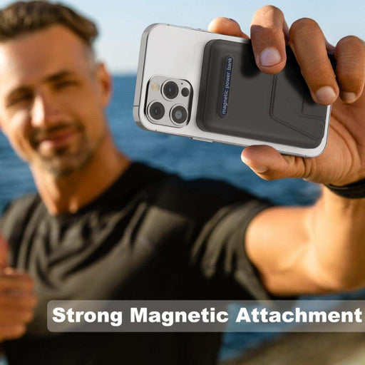 Man holding iPhone with magnetic wireless portable power bank outdoors, strong attachment shown TUTT