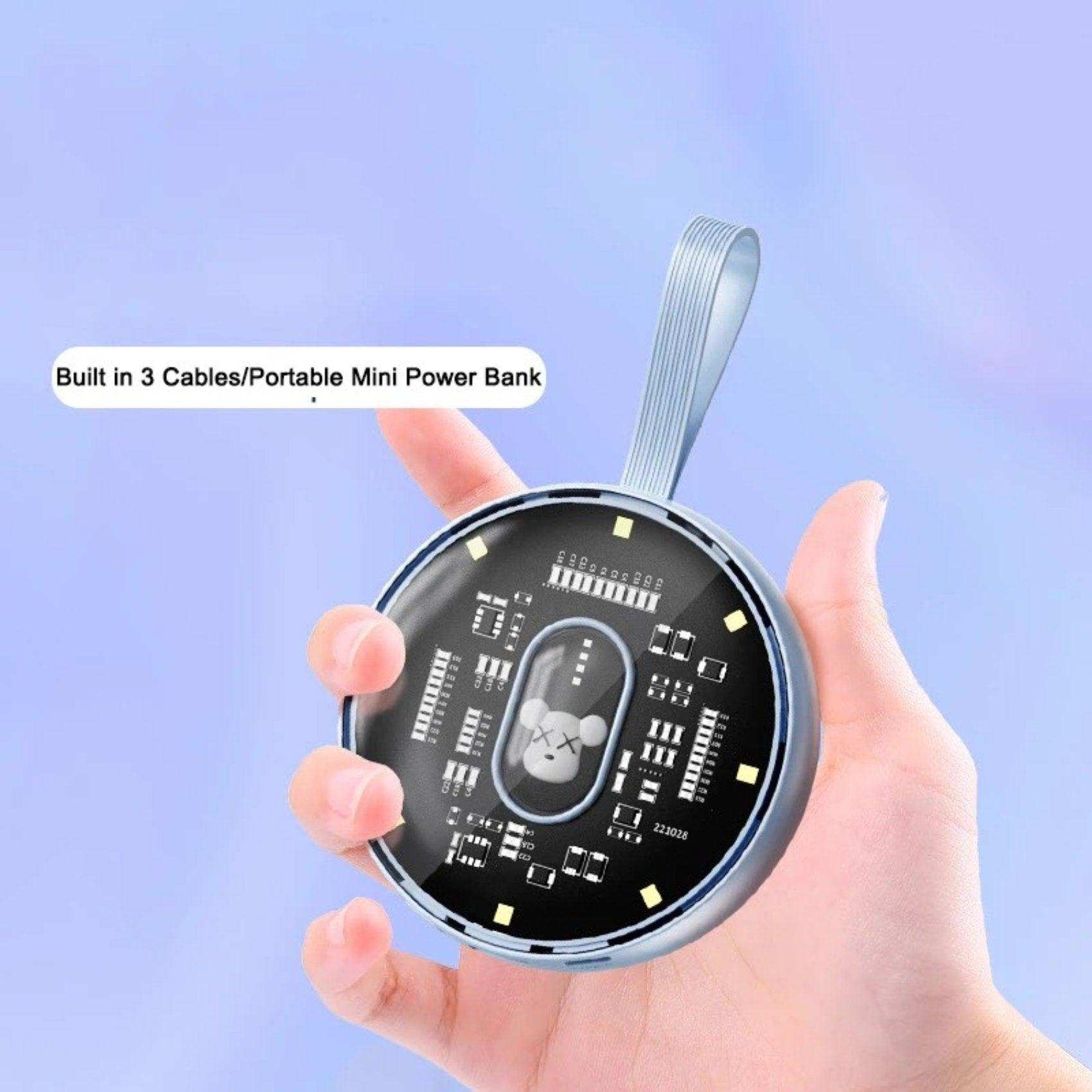 Hand holding round mini power bank with built-in cables, LED lights, bear decor, blue background TUTT