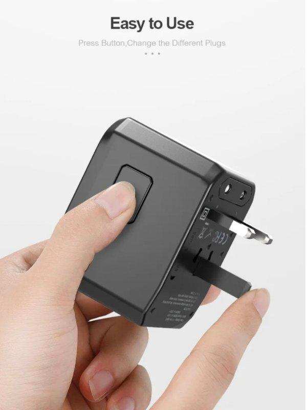 Hand holds black universal travel adapter with retractable US plug and easy-to-use button, TUTT