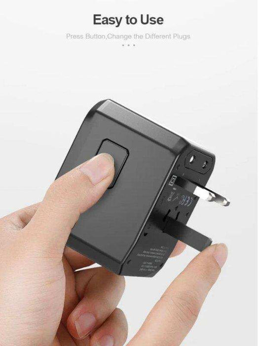 Hand holds black universal travel adapter with retractable US plug and easy-to-use button, TUTT