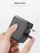 Hand holds black universal travel adapter with retractable US plug and easy-to-use button, TUTT